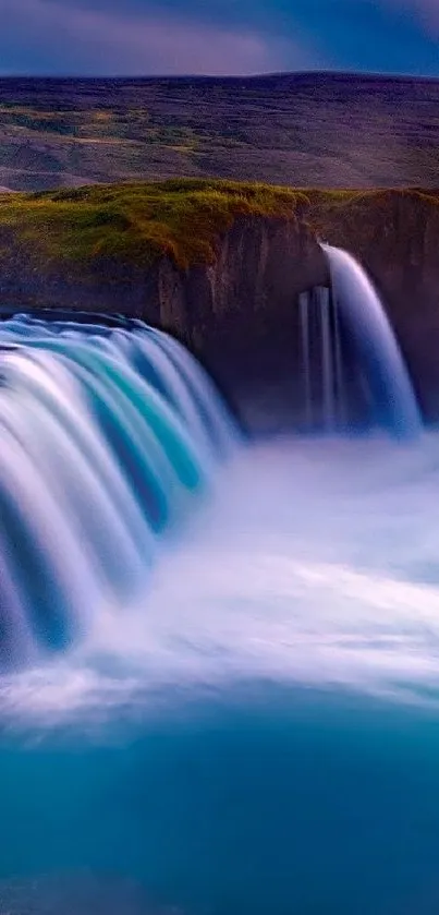 Blue waterfall cascading over rocky ledge in scenic natural landscape.