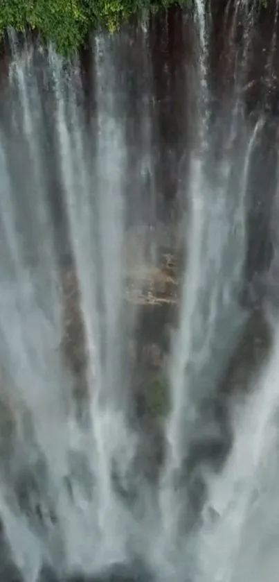 A stunning waterfall cascading down rocks, surrounded by lush greenery.