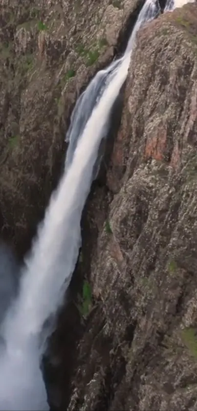 A stunning waterfall cascading down rugged cliffs into a misty pool.