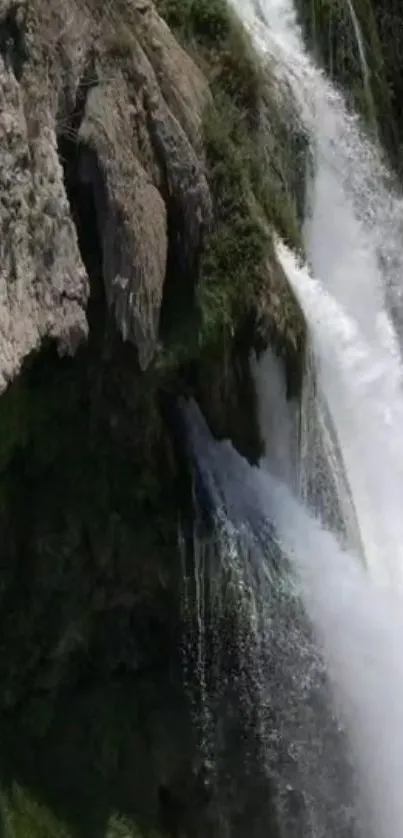 Cascading waterfall over rugged cliffs in a serene natural landscape.