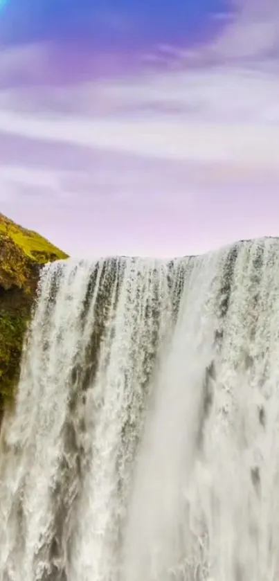 Waterfall against green cliffs with a rainbow in the sky.