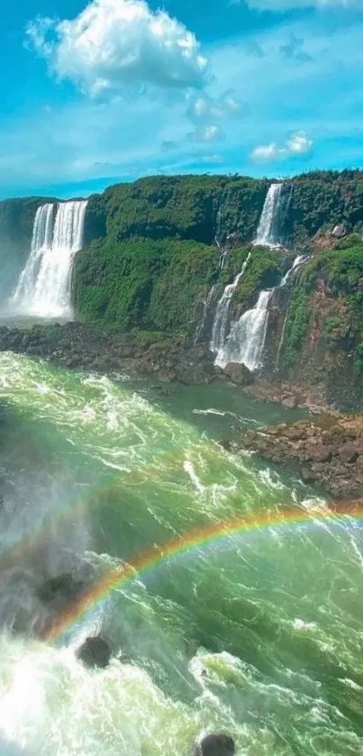 Mobile wallpaper of a waterfall with a rainbow under a clear blue sky.