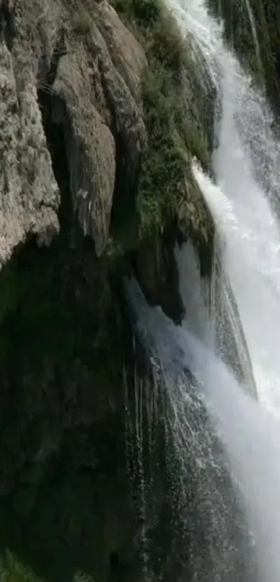 Majestic waterfall flowing over rocky cliff in nature scene.