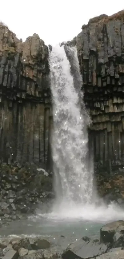 Waterfall cascading over dark rock formations in stunning mobile wallpaper.