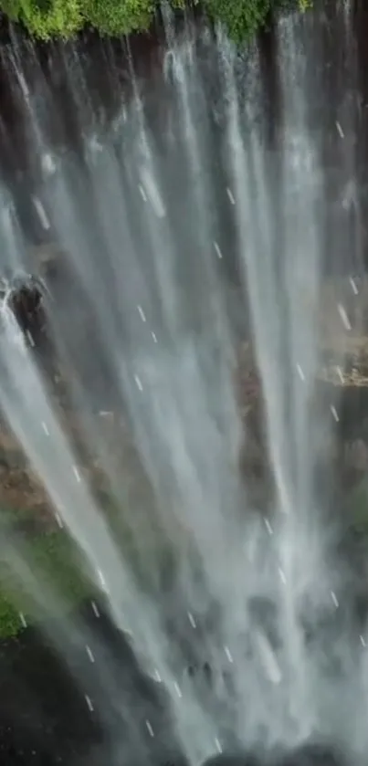 Vertical view of a stunning waterfall cascading down amidst lush greenery.