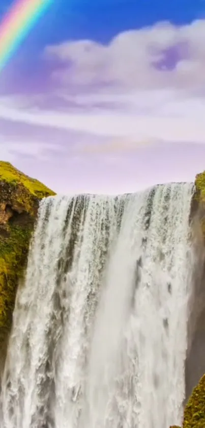 Vivid waterfall with a rainbow over lush green cliffs under a blue sky.