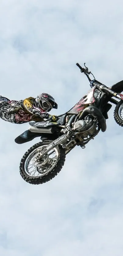 Stunt rider mid-air against a blue sky wallpaper.