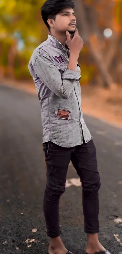 Stylish young man standing on a deserted street with autumn leaves in the background.