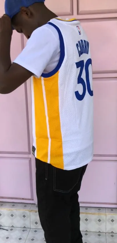 Person wearing a white basketball jersey with yellow stripes.