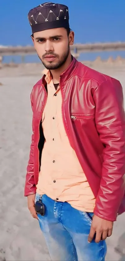 Young man in red jacket on the beach with a clear sky.