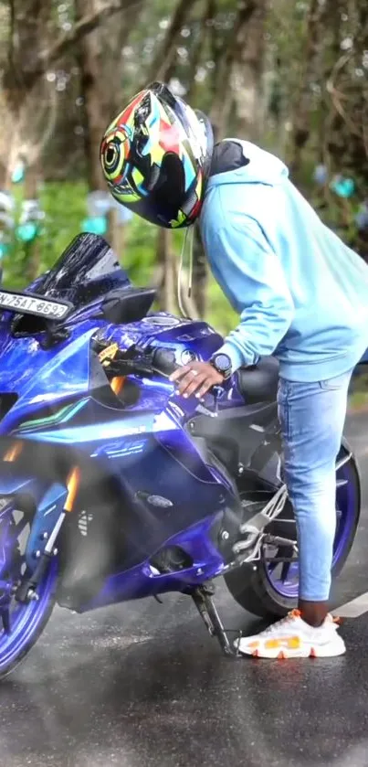 Biker in helmet poses with blue motorcycle on a scenic road.