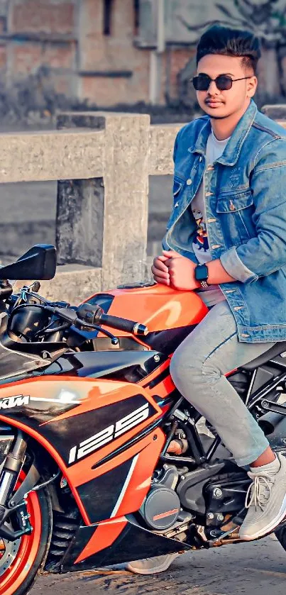 Young man on orange motorcycle by bridge.