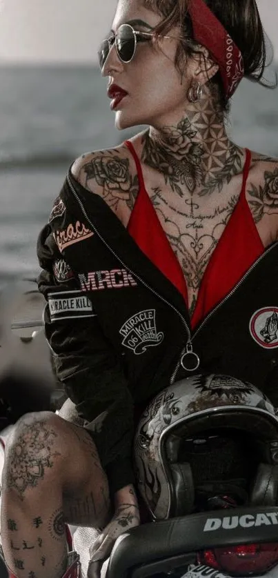 Tattooed biker woman on a motorcycle by the ocean.