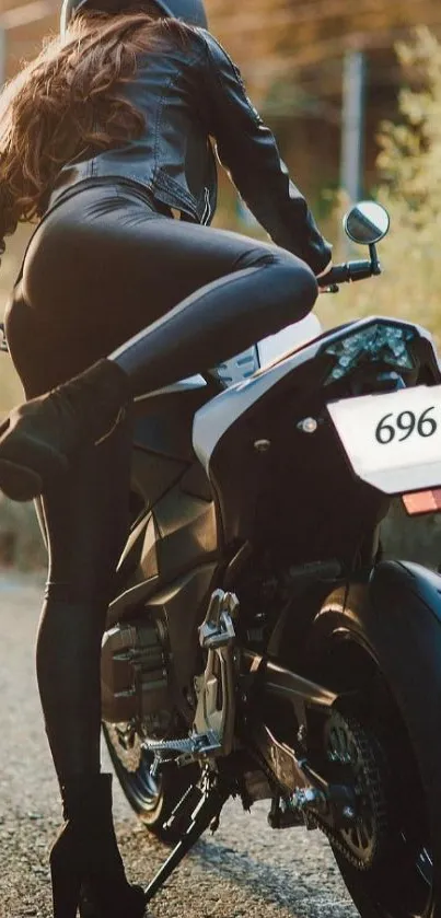 Rider in black leather on motorcycle in scenic setting.