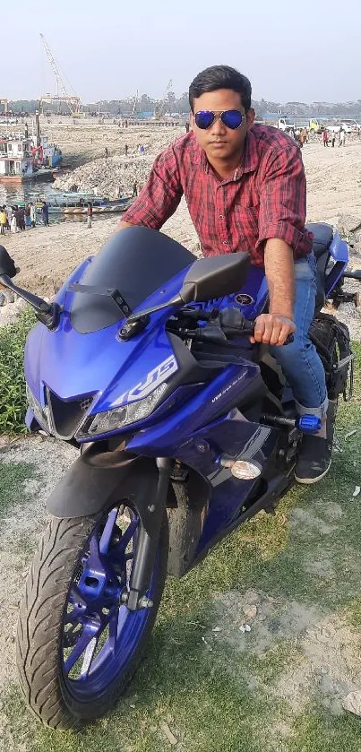 Stylish man on a blue motorcycle by the waterfront.