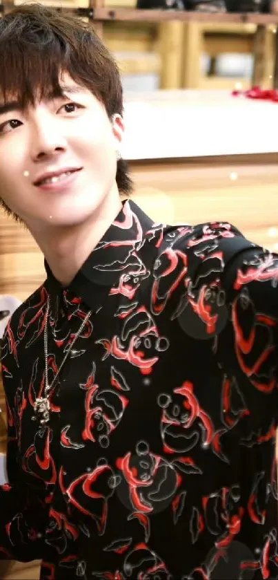 Person wearing a black shirt with a red cartoon pattern, taking a selfie indoors.