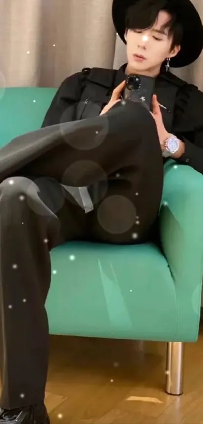 Person in black outfit seated on a teal chair.