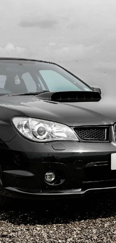 Elegant black car parked on gravel in scenic landscape.