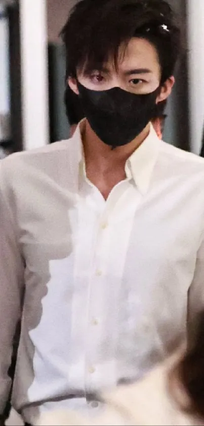 Person wearing a black mask and white shirt in a stylish setting.