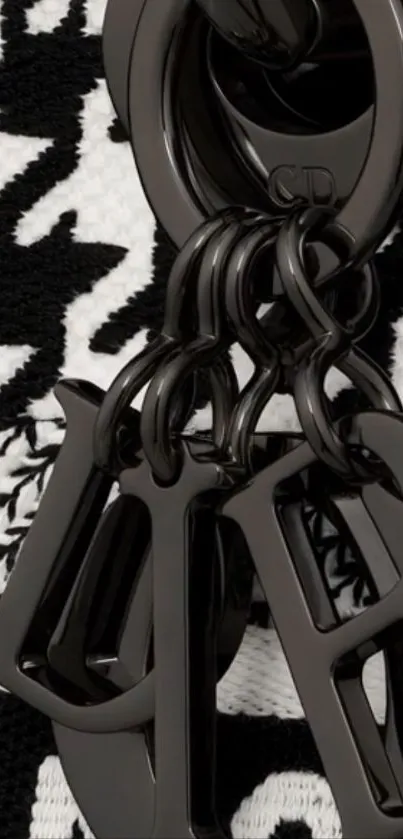 Black keychain with artistic pattern design on wallpaper.