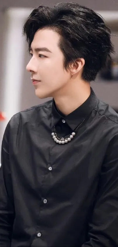 Person wearing a black shirt with stylish hair, looking sideways.