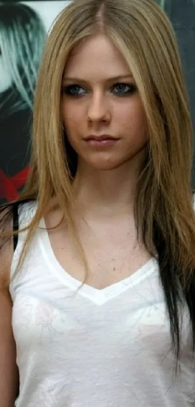 A stylish blonde woman in a white tank top stands against a grungy background.