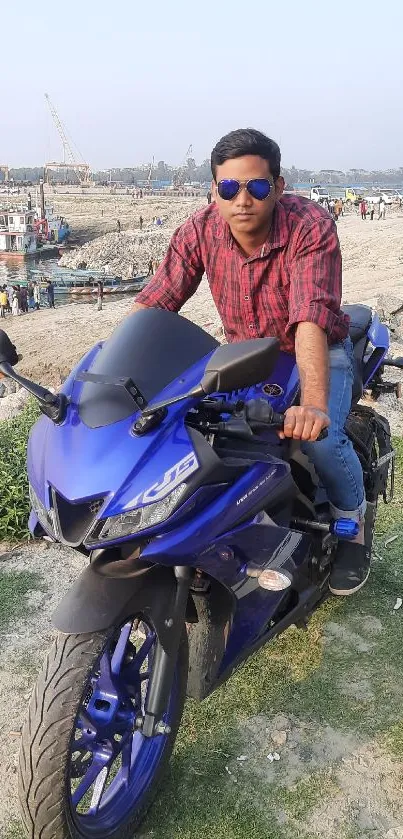 Man on blue motorcycle by the beach.