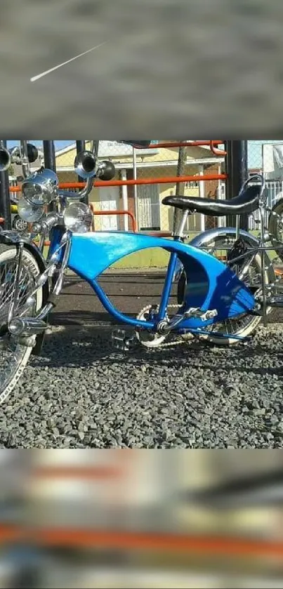 Vintage blue bicycle parked on gravel with a playground in the background.