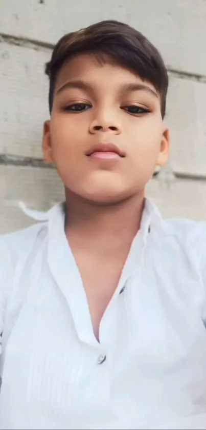Boy in a white shirt against a brick wall