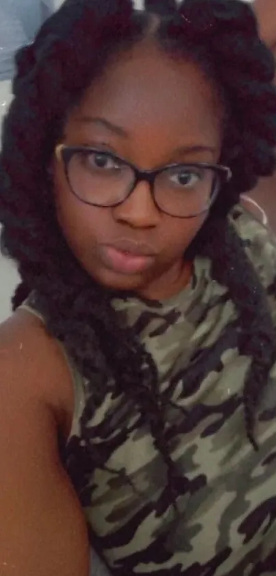 Woman with braids in camouflage top and glasses in portrait.