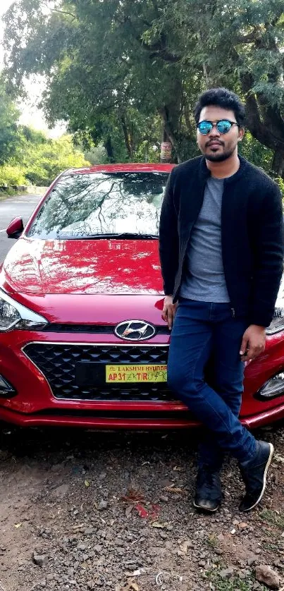 Person posing with a red car in nature.