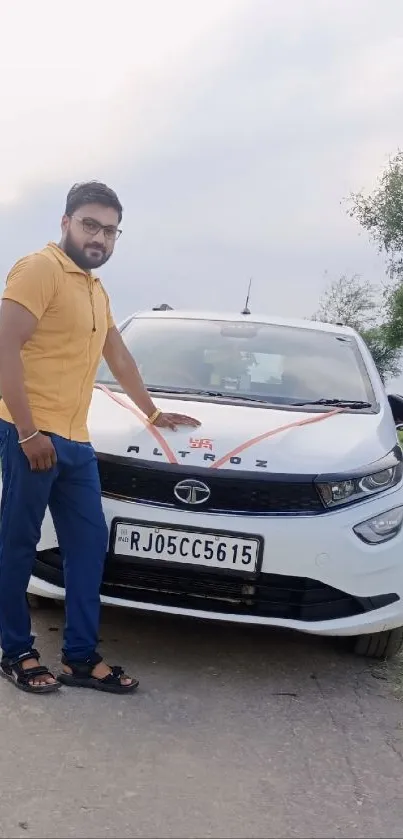 Man posing confidently beside a sleek white car on a country road.