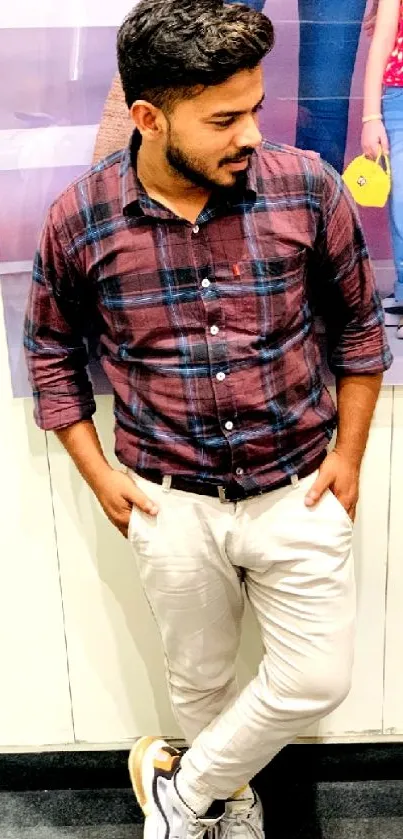 Man in stylish casual attire leaning against wall.