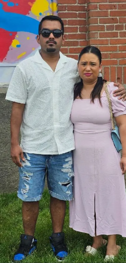 Casually dressed couple in front of a brick wall displaying urban chic style.