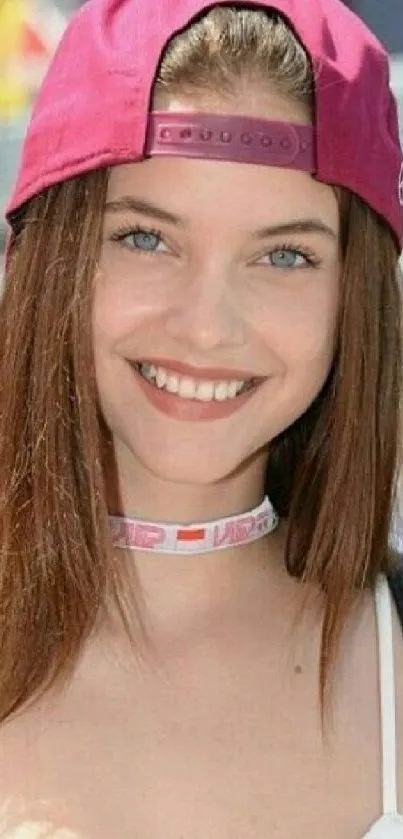 Girl in a pink cap smiling outdoors.