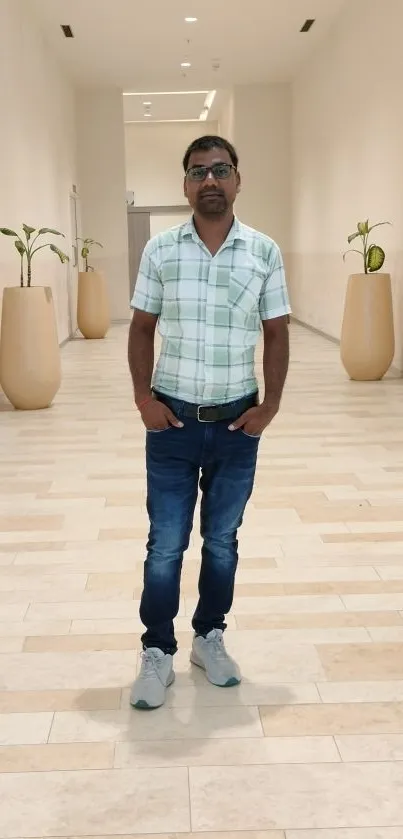 Casual man posing in stylish hallway with plants and modern decor.