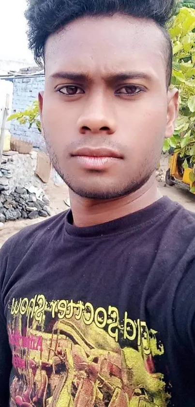 Young man in a black tee with urban outdoor background.