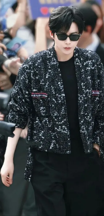 Stylish celebrity wearing a black sequin jacket surrounded by a crowd.