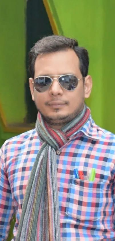 Person in checkered shirt with green backdrop and stylish accessories.