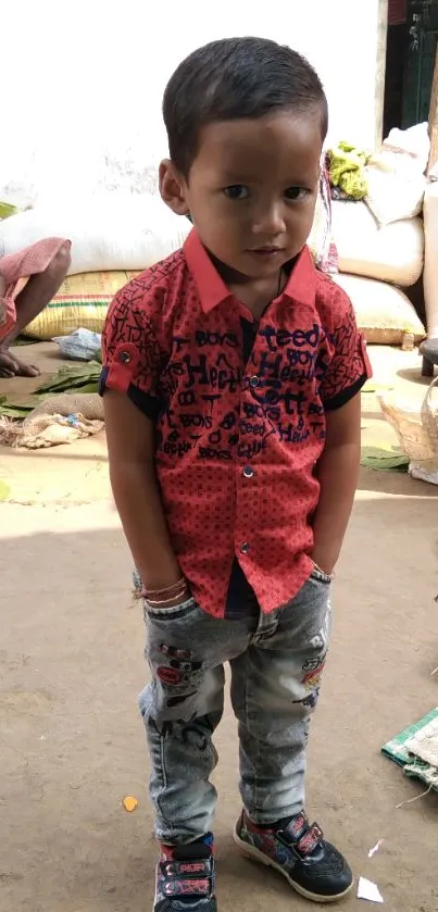 Young child in red shirt and jeans in a bustling outdoor market.