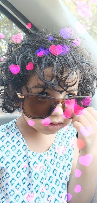 Child with sunglasses and curly hair in a car, stylish look.