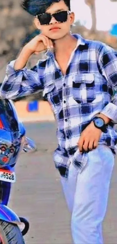 Cool young man in plaid shirt with sunglasses beside a motorbike.