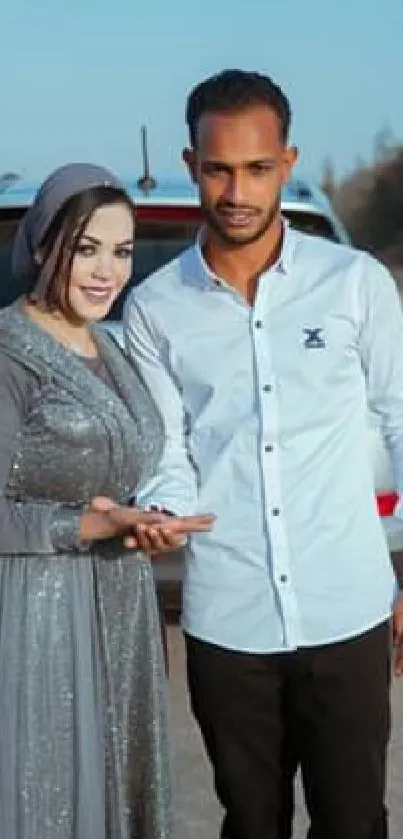 Stylish couple posing by car under clear blue sky.