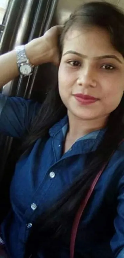 A young woman in denim shirt sitting inside a car.