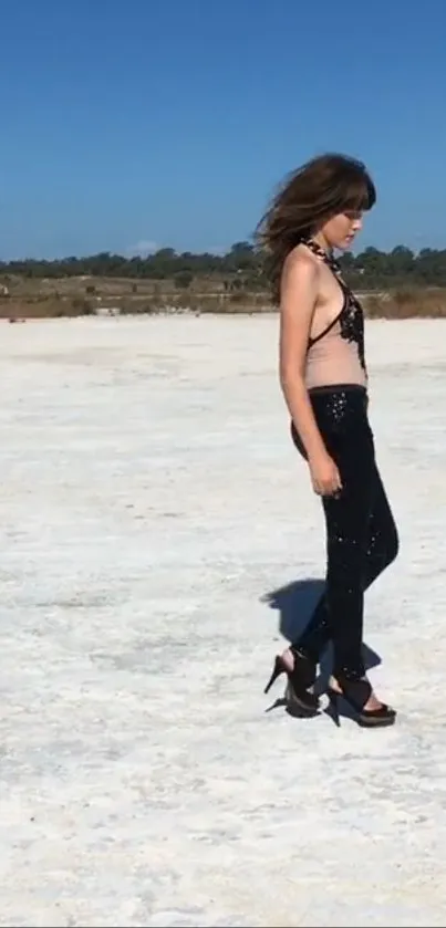 Woman walking stylishly across a sunlit desert.