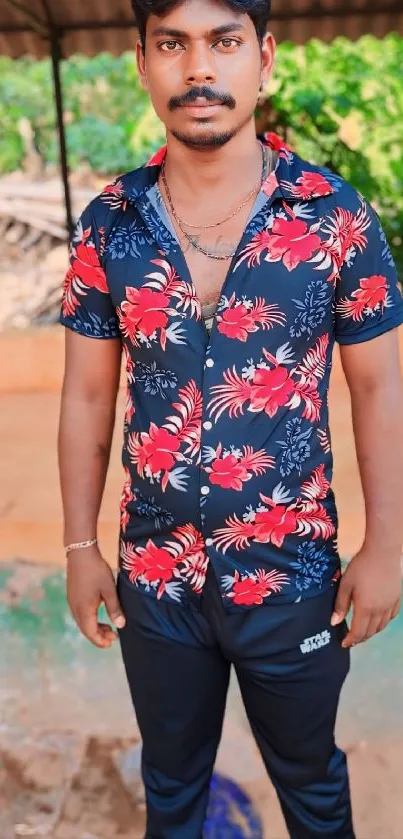 Man in red floral shirt with tropical background.