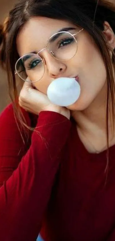 Stylish girl in glasses blowing bubblegum with red shirt.