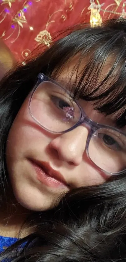 Girl with glasses against a rich red background.