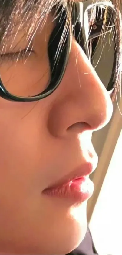 Close-up profile with glasses in sunlight, showcasing serenity.