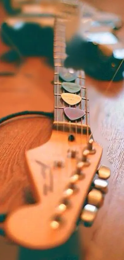 Close-up of guitar neck with picks on a wooden surface.